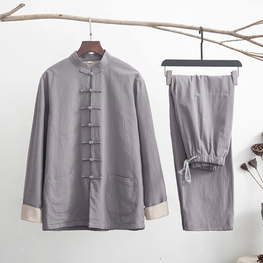 Men's linen zen tang suit set in light gray with traditional frog buttons and white contrast cuffs, displayed on side view with dry branch meditation props
