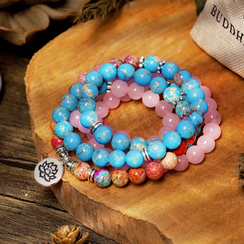 Pastel pink and blue Miano mala beads with lotus charm on wooden table and branded pouch - 108 bead Buddhist necklace