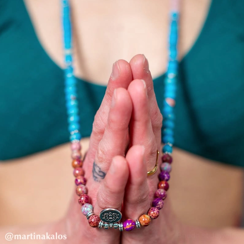 Close-up of purple and pink beaded mala necklace worn on chest with lotus metal pendant - Buddhist spiritual jewelry detail