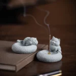 Mindful cat incense burner standing position with burning incense and smoke on wooden desk