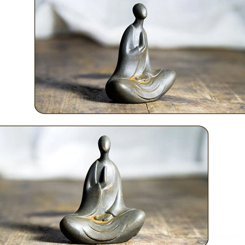Mini Buddha statue in dark gray with rusty yellow seat details shown from three-quarter top view on vintage wooden table