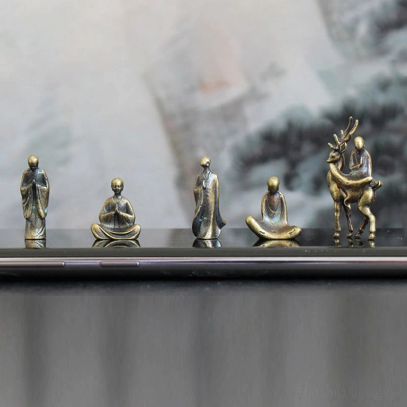 Mini bronze Buddha monk with graceful deer companion piece set, flat-lay glossy desktop display, complete meditation decor collection
