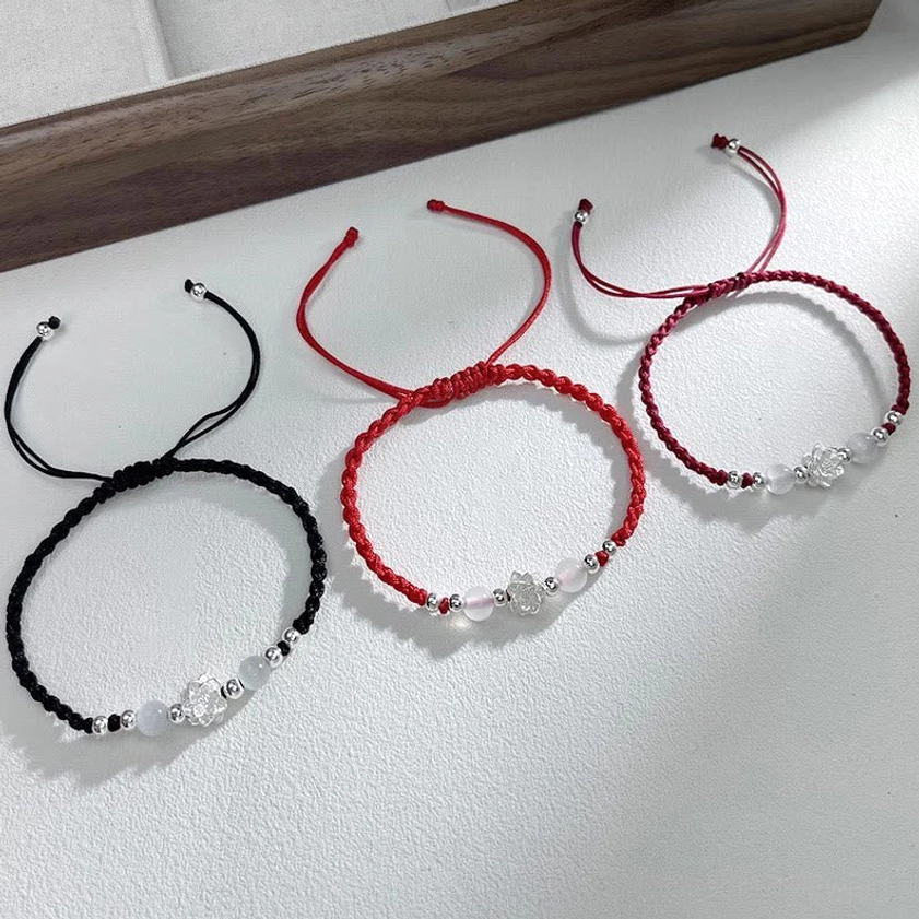 Minimalist sterling silver lotus bracelet with black thin cord and silver accent beads on light tabletop