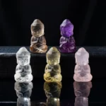 Multi-color carved Buddha crystal pendant collection - amethyst, pink crystal, white crystal, citrine, and smoky quartz Buddha figurines in flat lay display