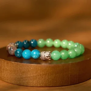 Mixed gemstone Buddha head bracelet with blue, pink, and light green stones on wooden display