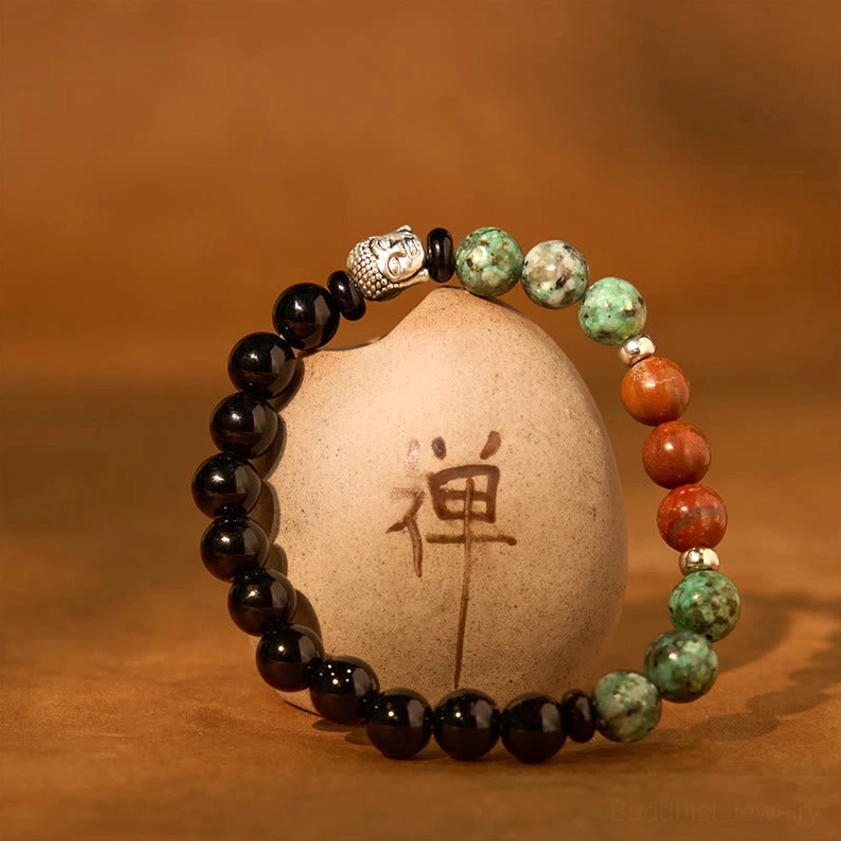 Mixed stone Buddha head bracelet with black, green, red, and brown beads on warm background
