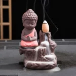 Monk backflow incense burner ceramic waterfall holder frontal view with pink robe and flowing incense smoke