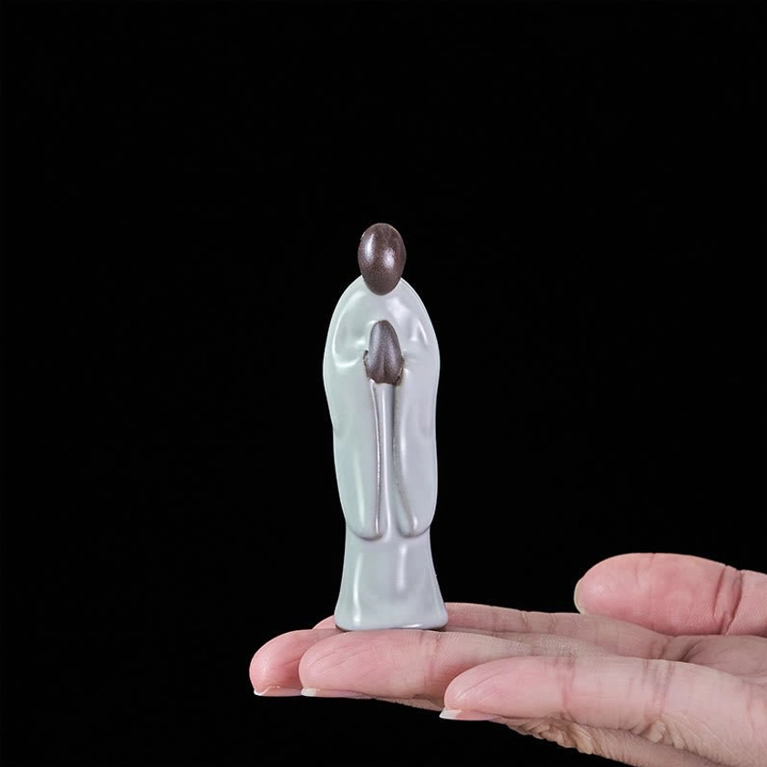 Compact ceramic meditation monk statue held in palm showing small portable size