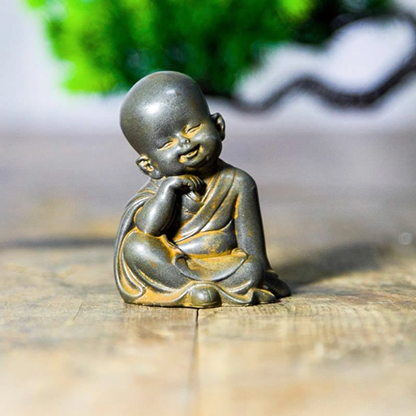Smiling Monk Covering Mouth - Iron Powder Resin Meditation Figurine with Green Plant Background