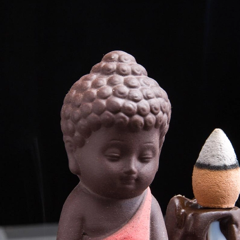 Close-up detail of ceramic monk's face and head showing carved hair texture and serene expression