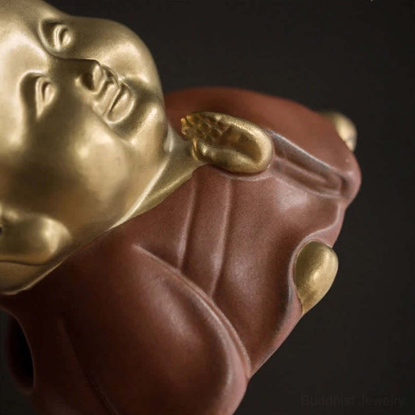Monk incense holder low-angle side close-up showing detailed robe texture and praying hand gesture, matte gold and brown ceramic