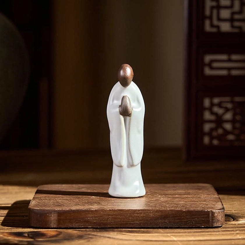 Meditation monk ceramic statue displayed on traditional wooden base and carved screen background