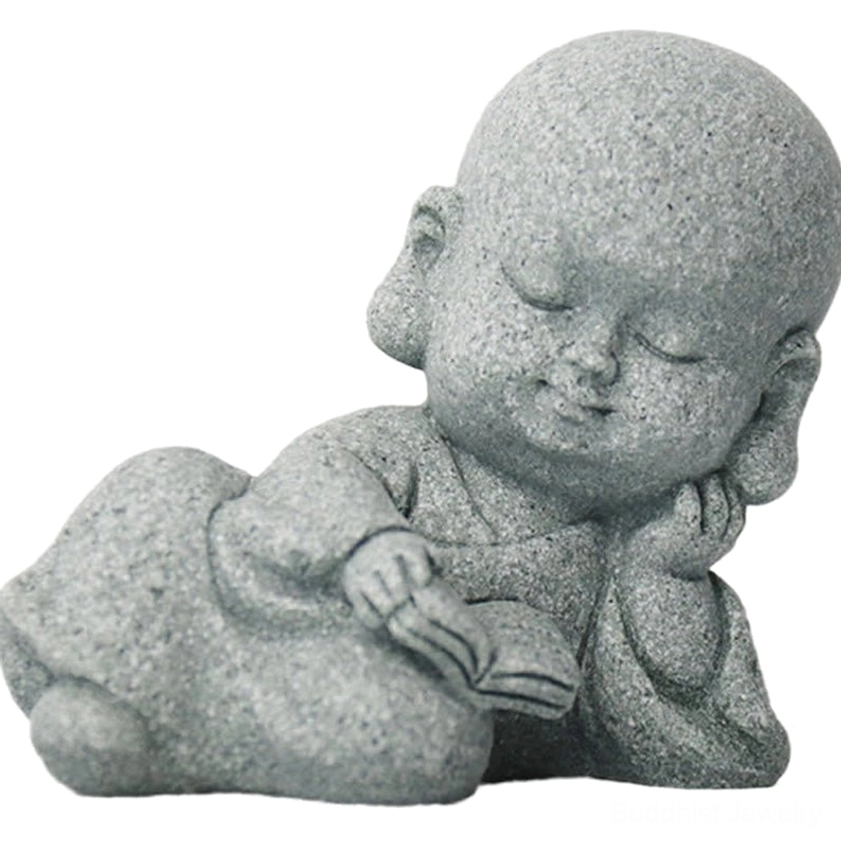 Smiling sitting monk with board Buddha statue on pebble stone surface - handcrafted meditation figure