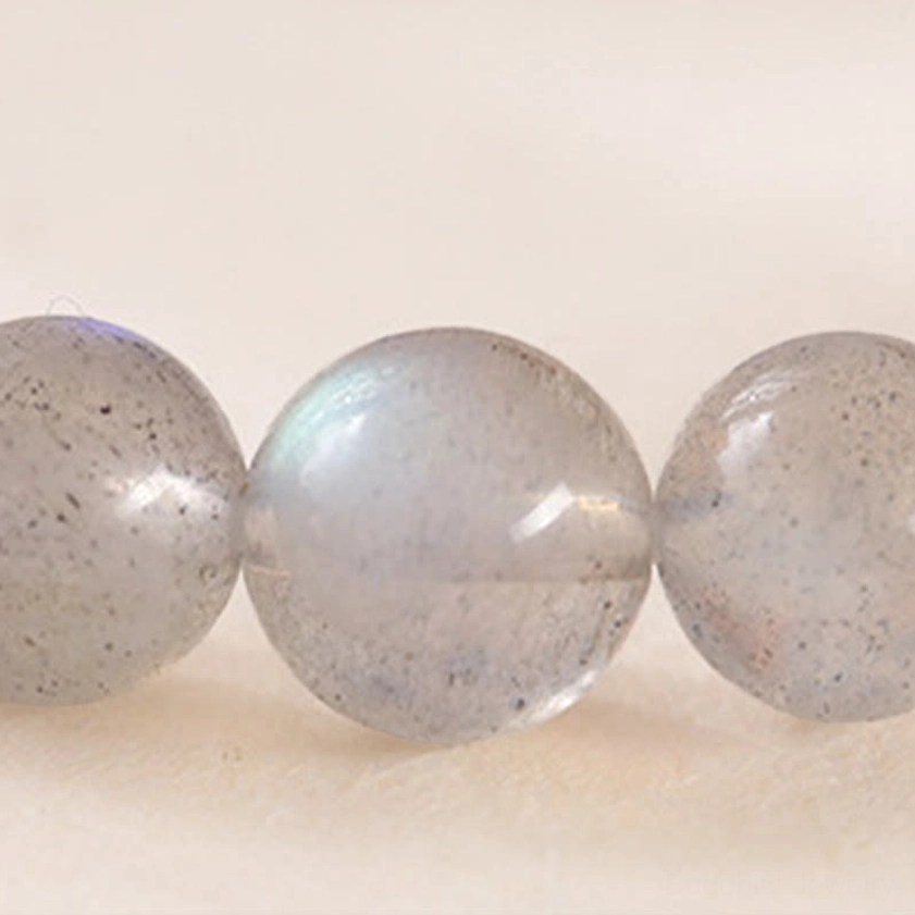Close-up macro photograph of moonstone beads showing semi-translucent texture, natural iridescent luster and subtle inclusions