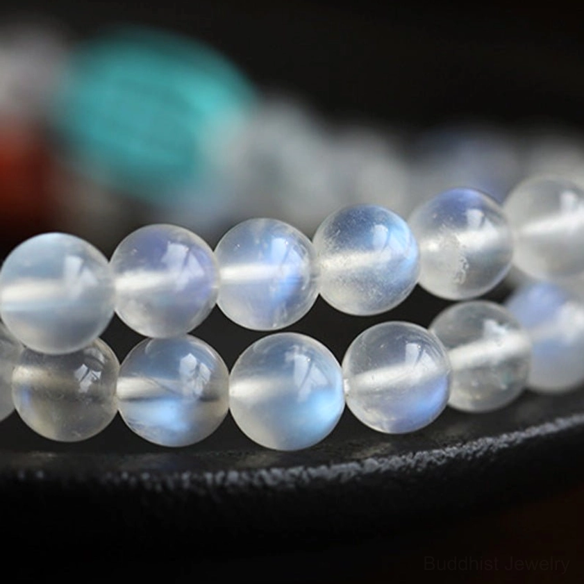Close-up of translucent moonstone beads with blue iridescent texture on black ceramic plate