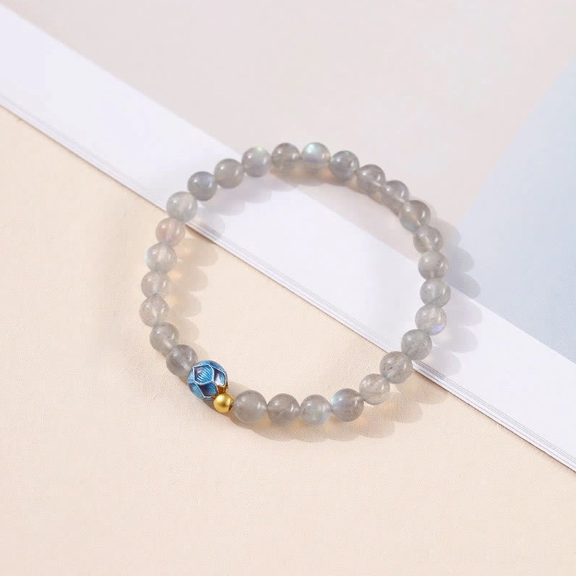 Moonstone Buddhist bracelet with blue lotus and gold beads arranged on white card, side angle photography for product showcase