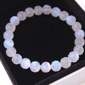 Natural moonstone lotus carved bracelet beads with blue iridescent shimmer, displayed overhead on black jewelry tray