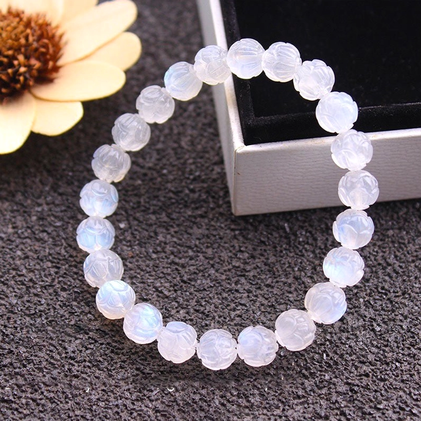 Moonstone lotus carved beads arranged neatly overhead view showing intricate lotus carving and milky translucent quality