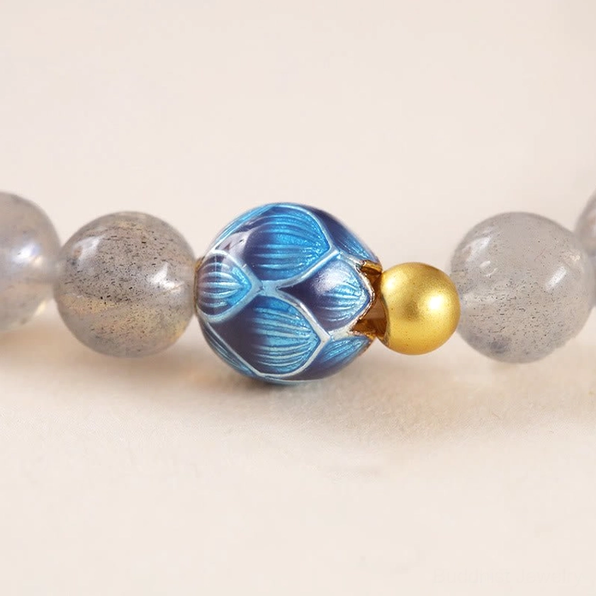 Detailed view of bracelet components showing blue lotus enamel charm, gold copper accent bead and gray moonstone bead coordination