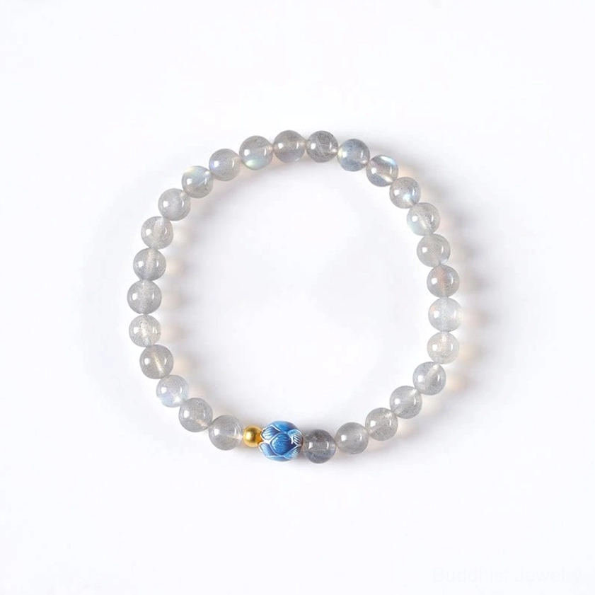 Moonstone lotus Buddhist bracelet front view flat lay showing complete strand with moonstone beads, carved lotus charm and gold bead details