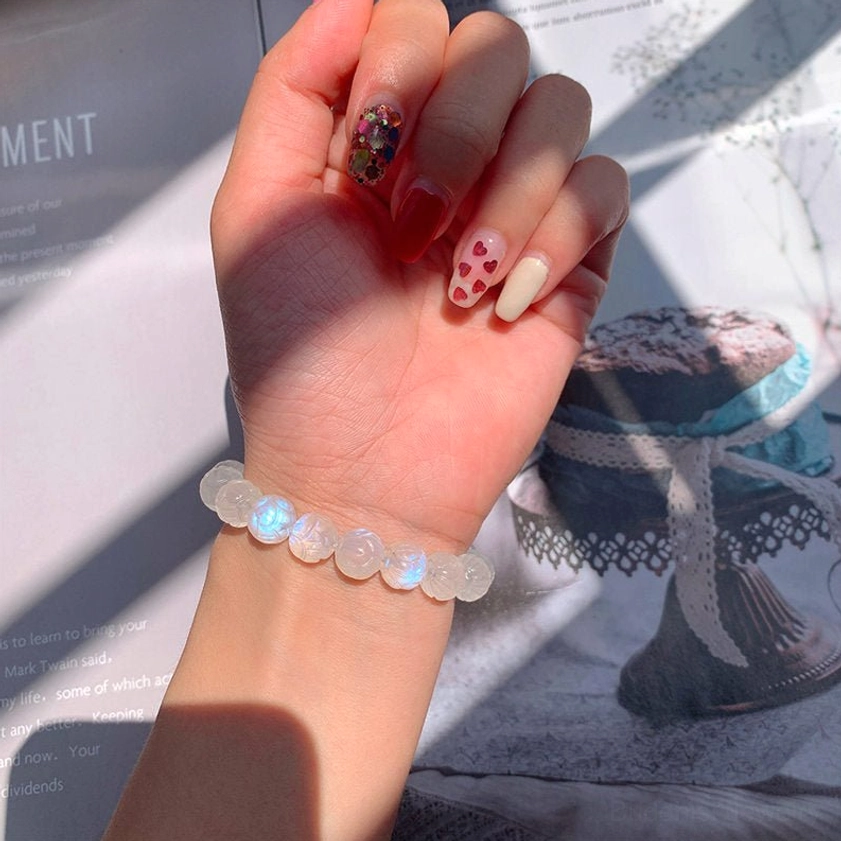 Moonstone lotus bracelet worn on female wrist, indoor lifestyle shot showing comfortable fit and elegant appearance