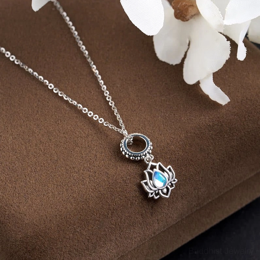 Dual pendant sterling silver moonstone necklace with engraved ring and lotus charm on velvet display with white orchid decoration