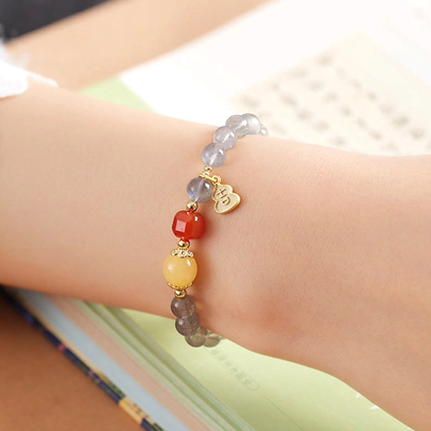 Complete view of moonstone red agate Buddhist bracelet showing beads arrangement with blue lotus charm and protective energy symbolism