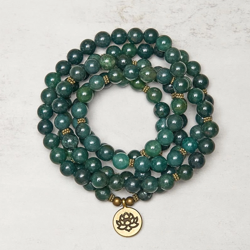 Moss agate 108 bead Buddhist prayer mala flat lay with gold lotus charm pendant, round green marbled agate beads with gold spacers on neutral background
