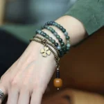 Moss agate copper healing bracelet worn on wrist with brass clover charm and wooden pendant - Buddhist spiritual jewelry