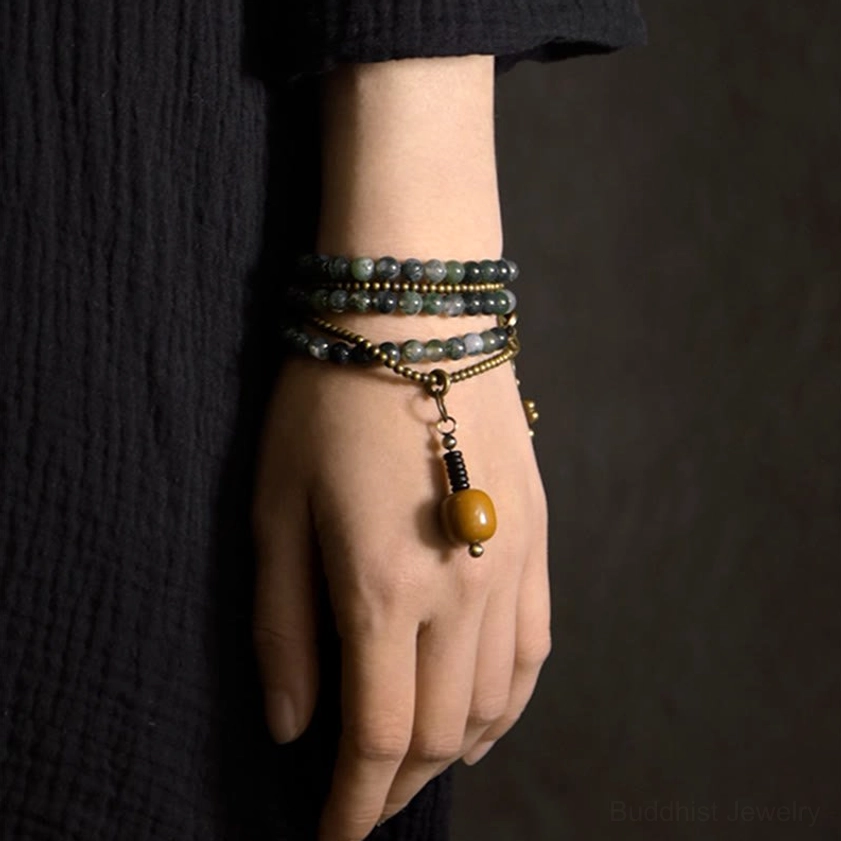 Stacked moss agate and brass bead bracelet worn on wrist showing layered healing crystal design