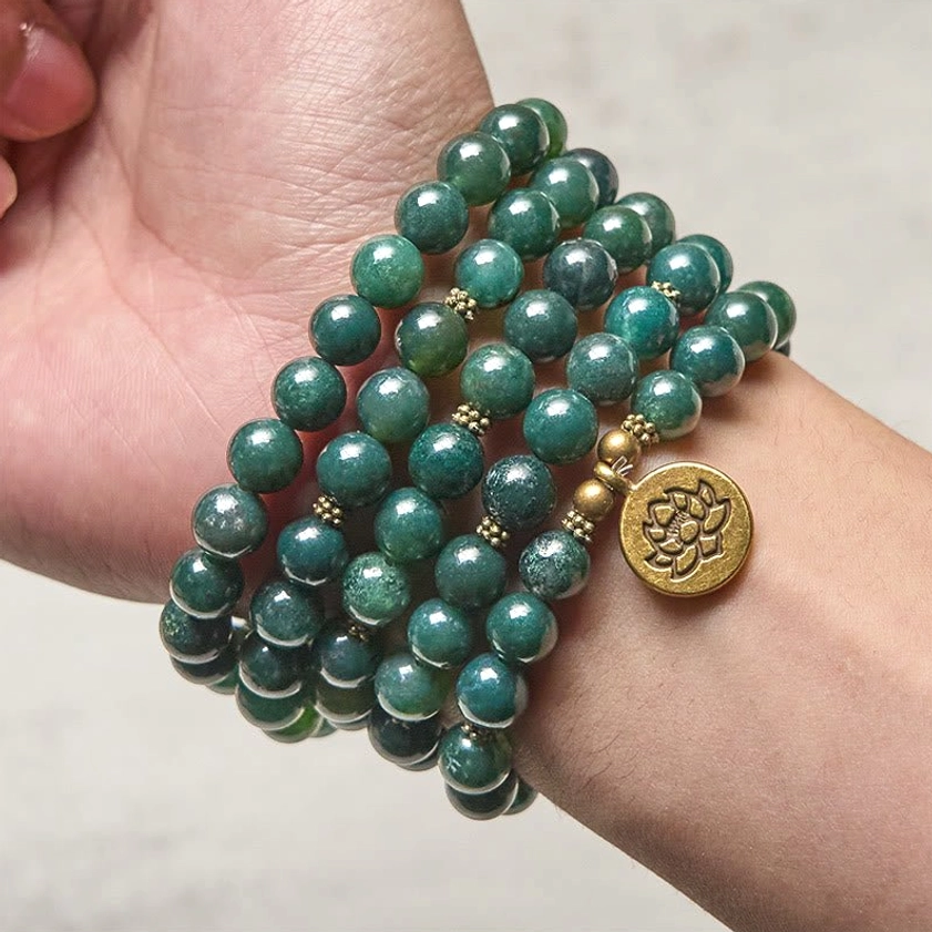 Moss agate prayer mala worn as multi-layer wrap bracelet on wrist with gold lotus charm accent and green marbled agate beads