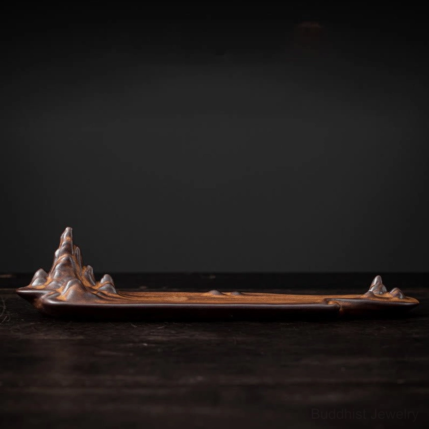 Flat side view of mountain ceramic incense burner displaying brown wood-grain texture and empty incense stick slot on dark wooden surface