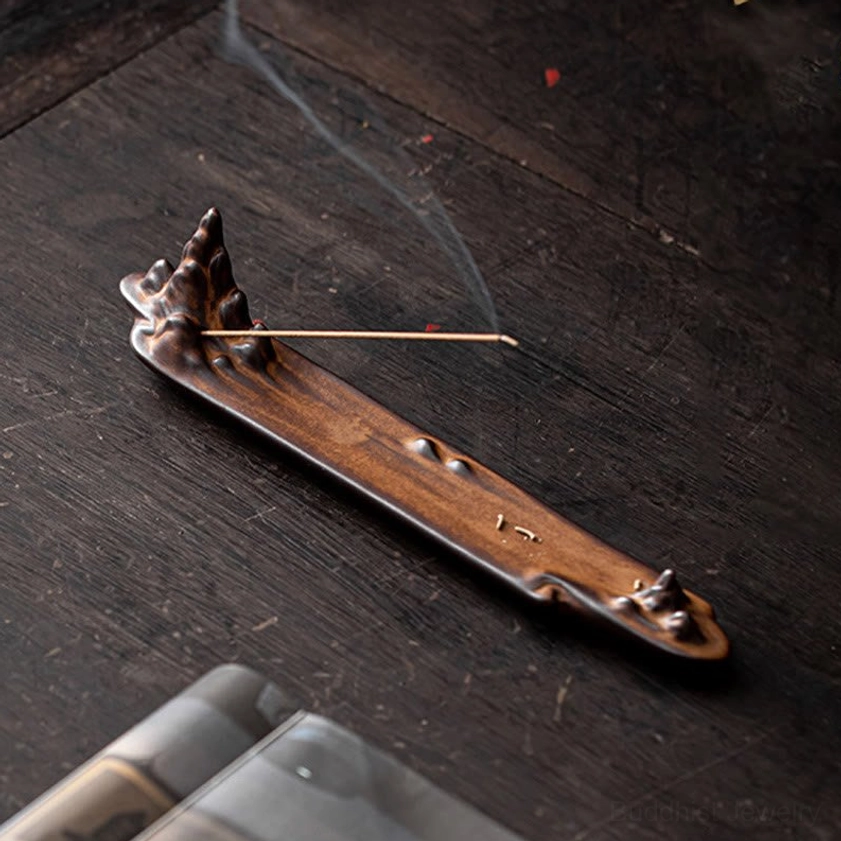 Top-down angled view of ceramic mountain incense holder burning incense with curling smoke visible, showcasing mountain peak carved design detail