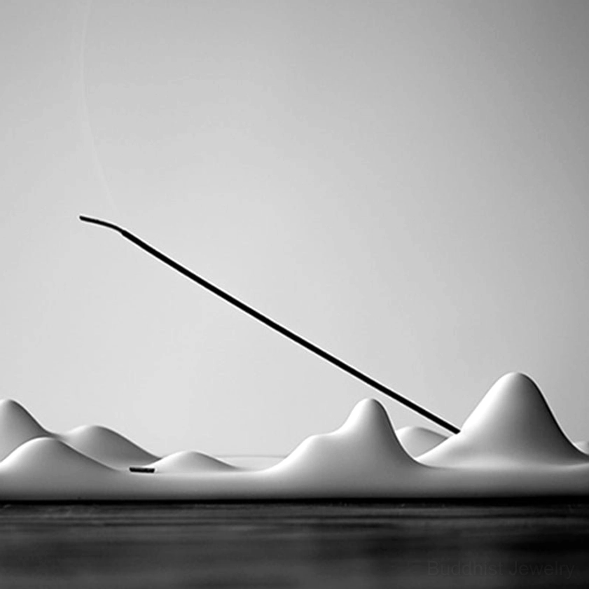 Gray ceramic mountain peak incense burner with lit incense stick, side angle view