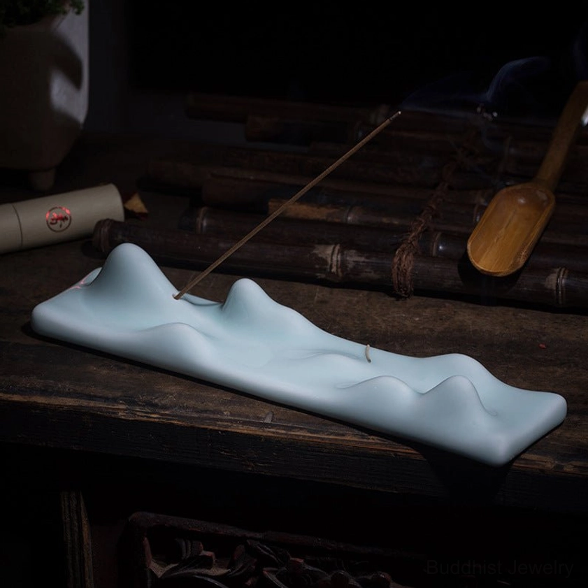 Pale blue mountain peak incense holder three-quarter view on antique wooden tea table with accessories