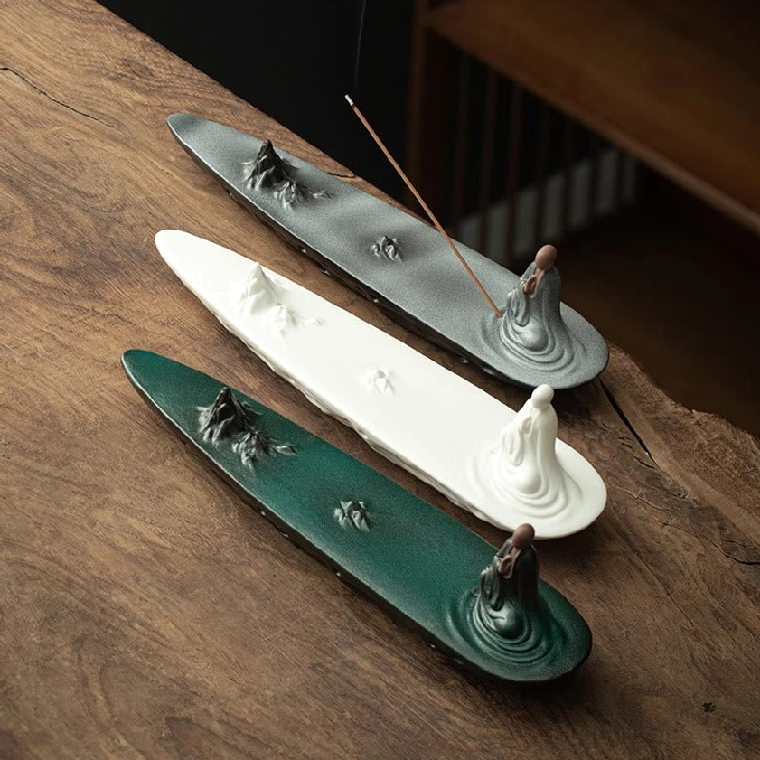 Three handcrafted ceramic incense holders in white gray and green with Buddhist monk and mountain decorations