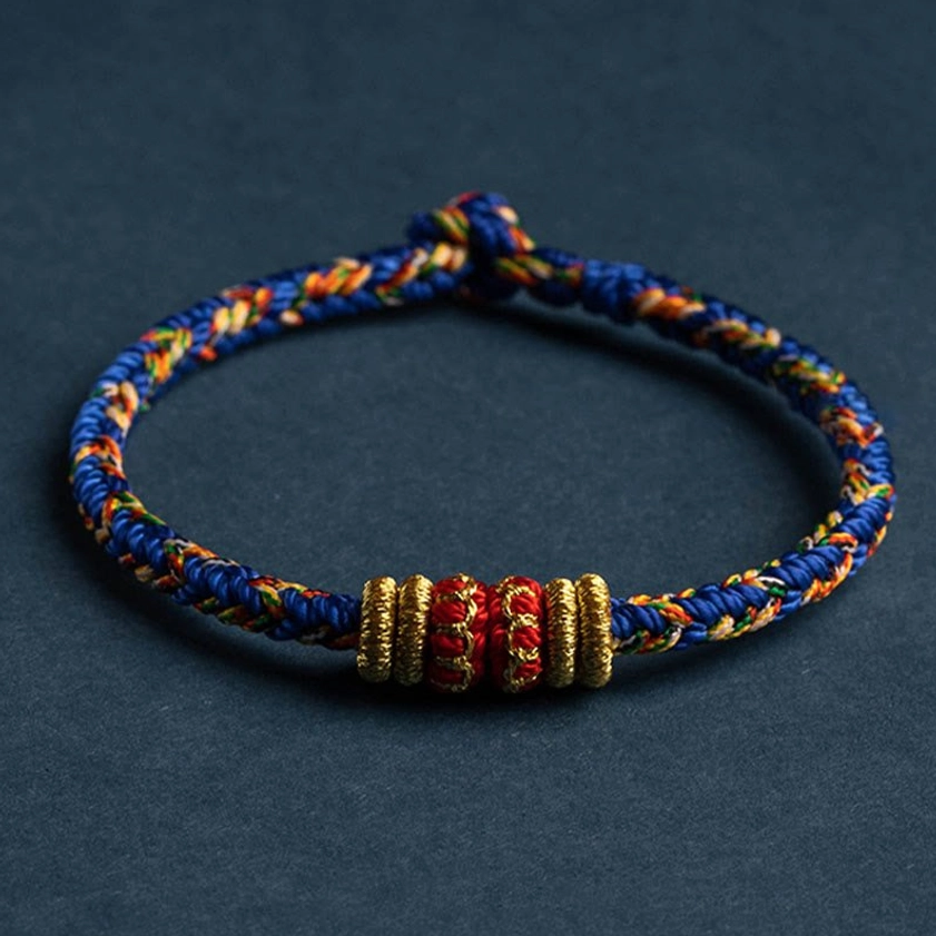 Multicolor blue handwoven buddhist string bracelet with gold and red protective knots detail