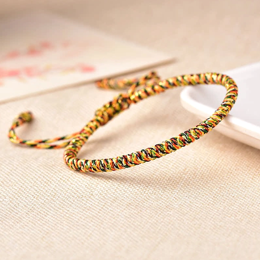 Handwoven multicolor Buddhist string bracelet with gold, yellow, green and red spiral braided texture and pull-cord design