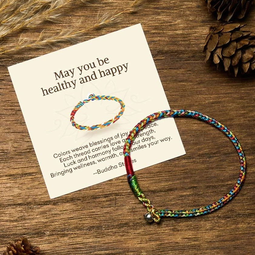 Multicolor Buddhist blessing bracelet with 925 silver clasp, gift message card and pinecones on wooden table - top view