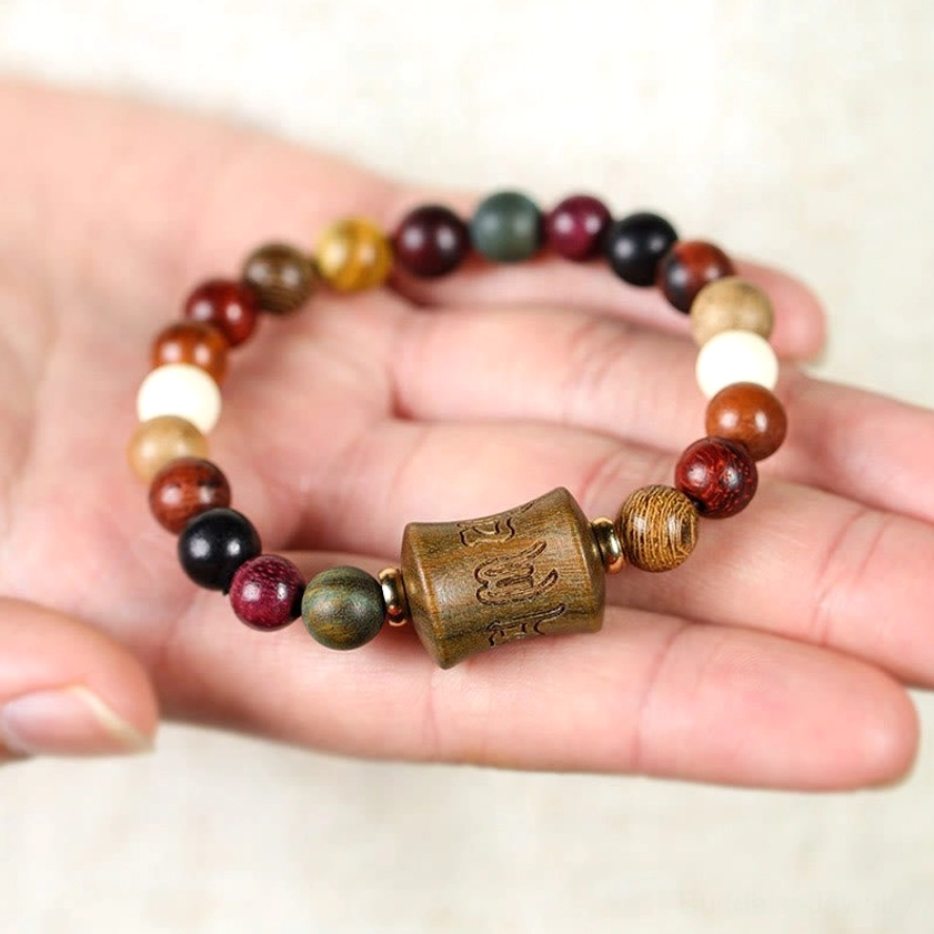 Sandalwood Om Mani Padme Hum bracelet resting on open palm, displaying natural bead colors and carved focal point