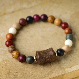 Multicolor sandalwood Om Mani Padme Hum prayer bracelet with carved mantra bead, top-down flat lay view