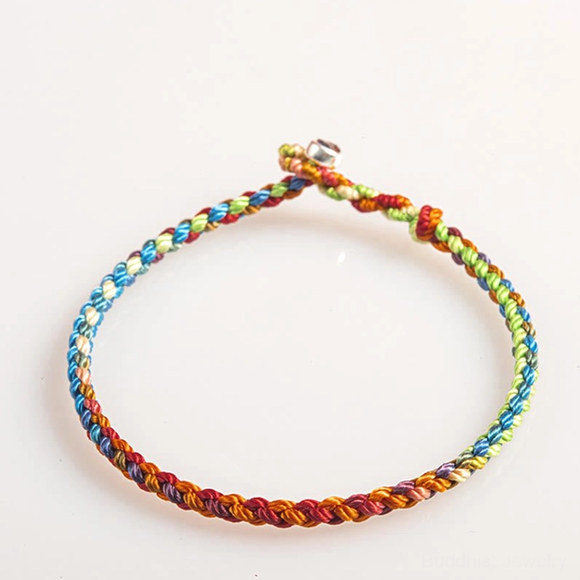 Artisan-made multicolored braided Buddhist bracelet with small bell clasp and vibrant rainbow cord weave