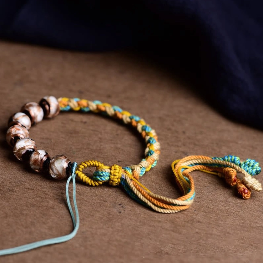 Front view of multicolored woven rope bracelet showing braided knot and round glass beads