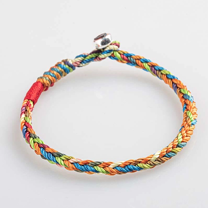 Multicolored woven Buddhist bracelet flat lay showing red thread accent and metal clasp design