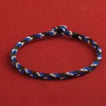 Multicolored hand-knotted Buddhist string bracelet with King Kong knot clasp, top-down view showing tri-color weave