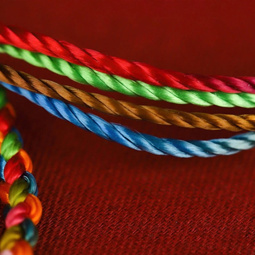Four-strand twisted multicolored Buddhist cord showing glossy silk finish and parallel weave arrangement