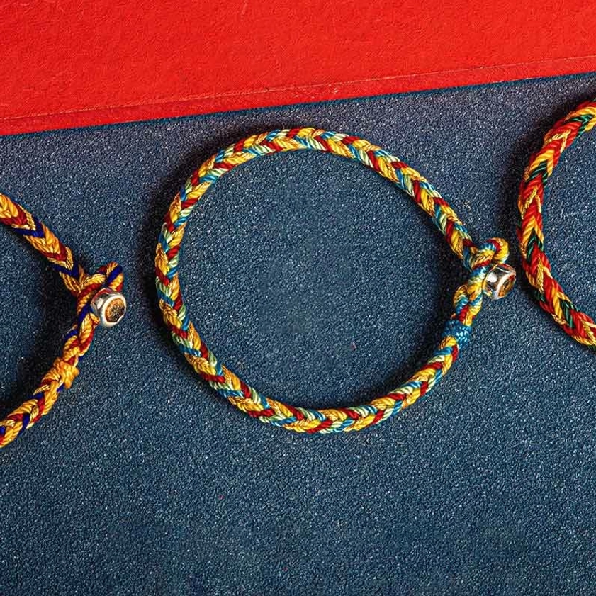 Partial views of multiple handwoven multicolored Buddhist protection bracelets showing twisted rope texture and mixed color threads