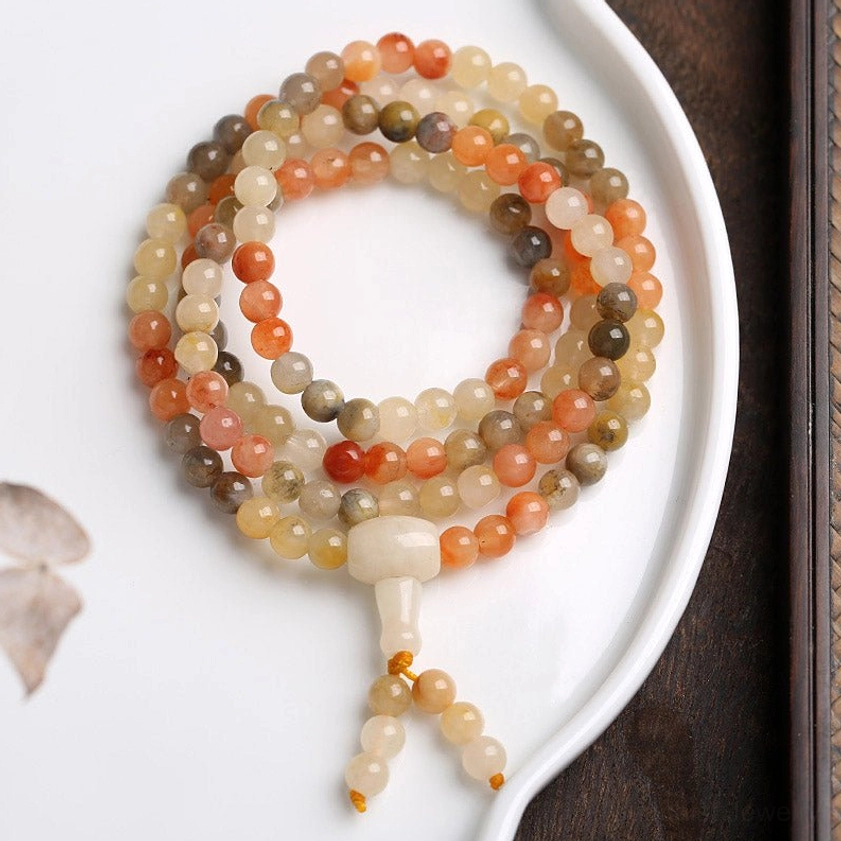 Natural agate mala prayer beads close up showing smooth polished beads in warm tones - overhead product photography