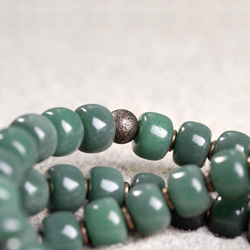 Close-up of bodhi seed beads with bronze metal spacers showing natural dark speckles and matte finish