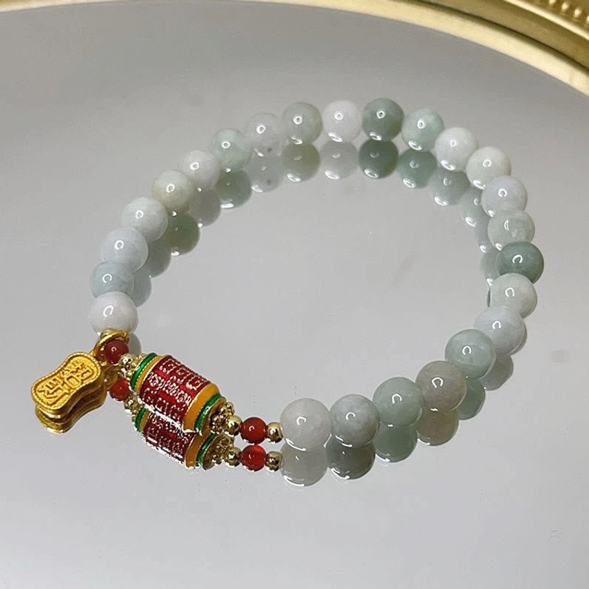 Complete jade prayer wheel bracelet collection with matching charms displayed on white gold-trimmed tray